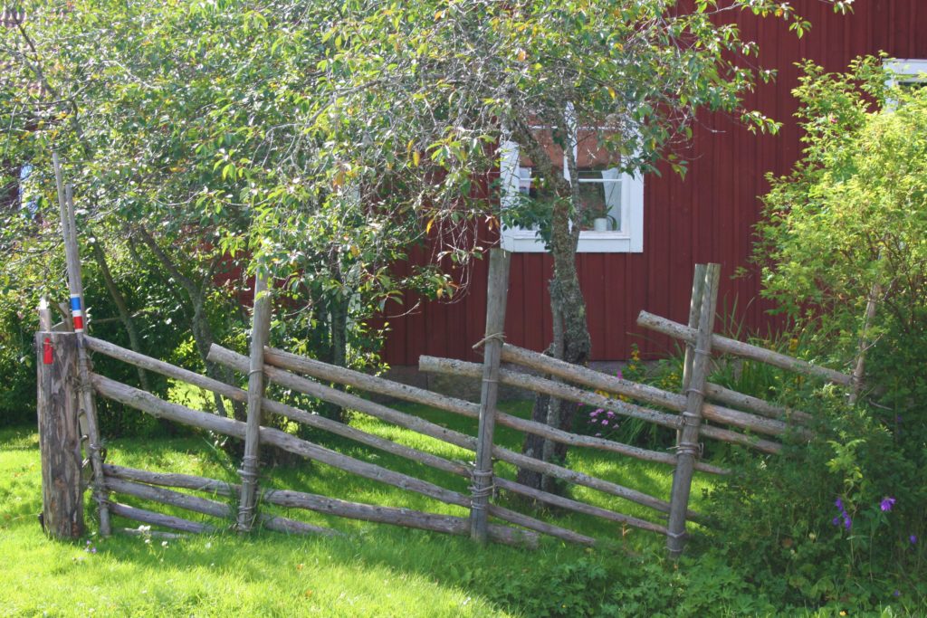 rotes Häuschen weiße Fenster Schweden Zaun Baum Büsche
